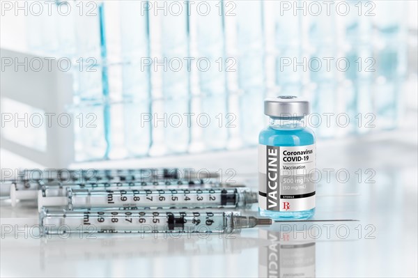 Coronavirus COVID-19 vaccine vial and several syringes on reflective surface near test tubes