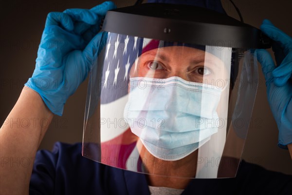 American flag reflecting on female medical worker wearing protective face mask and shield