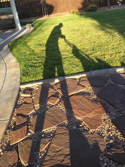 Shadow of man pushing lawn mower over grass