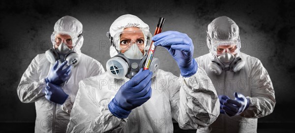 Team of doctors or nurses in hazmat gear holding positive coronavirus test tube banner