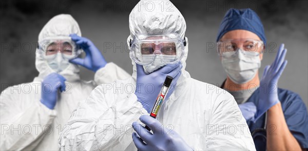Team of doctors or nurses in hazmat gear holding positive coronavirus test tube banner
