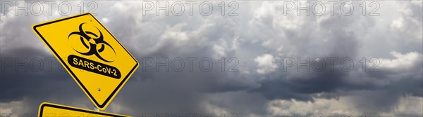 Bio-hazard symbol with sars-cov-2 coronaravirus yellow road sign against ominous stormy cloudy sky