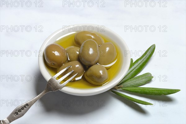Green olives in bowl with olive oil