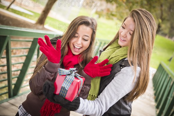 Two attractive mixed-race women having a gift exchange outside