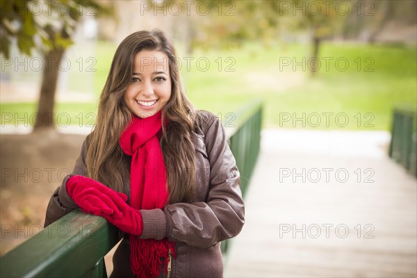 Pretty festive smiling woman portrait wearing a red scarf and mittens outside