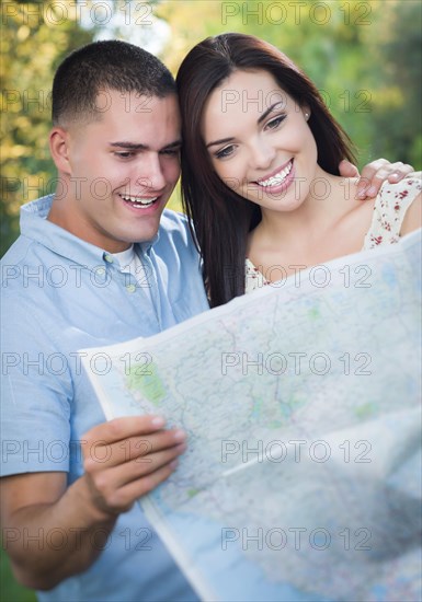 Happy mixed-race couple looking over A map outside together