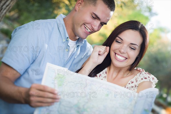 Happy mixed-race couple looking over A map outside together