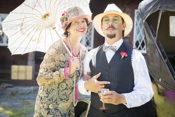 Attractive mixed-race couple dressed in 1920's era fashion sipping champagne