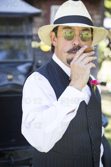 Handsome 1920s dressed man near vintage car smoking A cigar