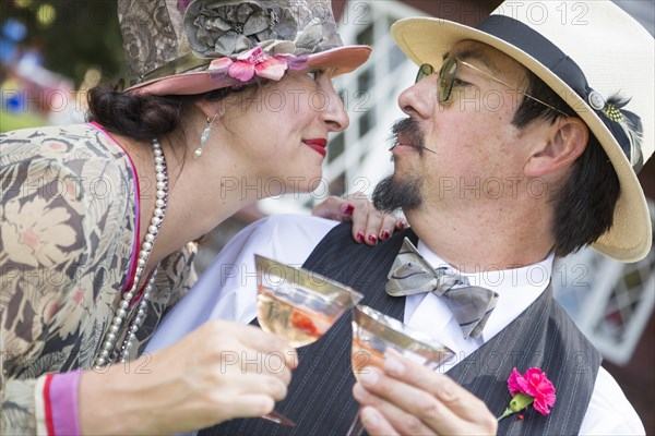 Attractive mixed-race couple dressed in 1920's era fashion sipping champagne