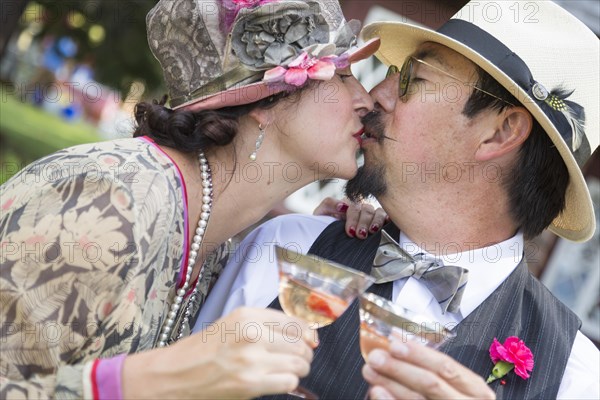 Attractive mixed-race couple dressed in 1920's era fashion sipping champagne