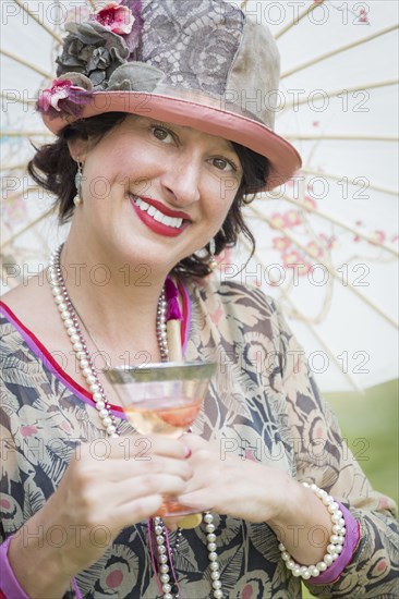 Beautiful 1920s dressed girl with parasol and glass of wine portrait