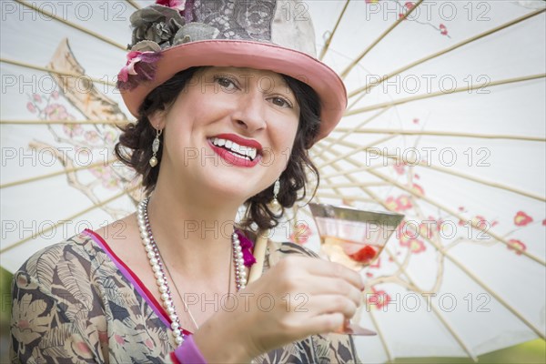 Beautiful 1920s dressed girl with parasol and glass of wine portrait