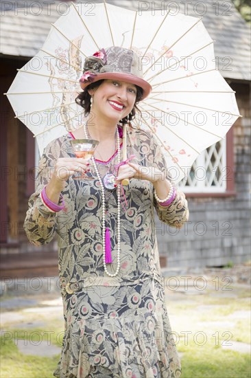 Beautiful 1920s dressed girl with parasol and glass of wine portrait