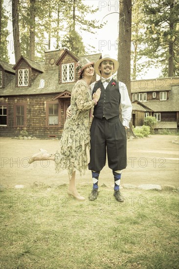 Attractive 1920s dressed romantic couple in front of old cabin portrait