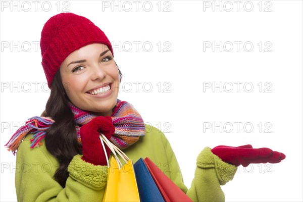 Beautiful mixed-race woman wearing winter hat and gloves isolated on a white background gesturing with her hand to the side