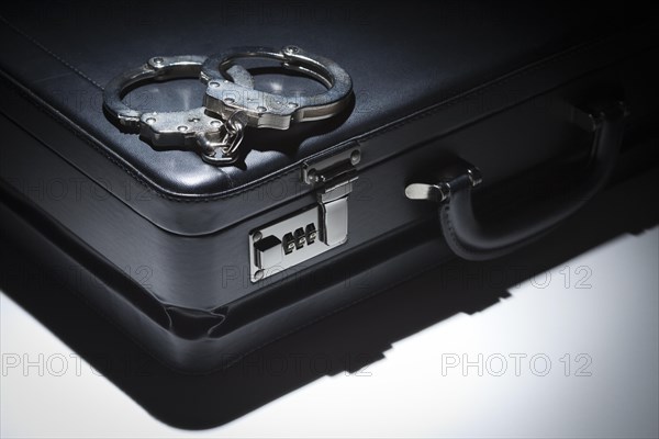 Pair of handcuffs and briefcase under spot light abstract