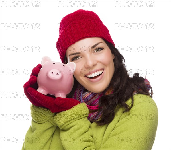 Happy smiling mixed-race woman wearing winter clothing holding piggybank isolated on white background