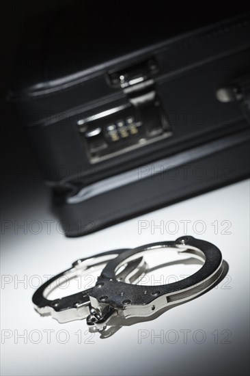 Pair of handcuffs and briefcase under spot light abstract