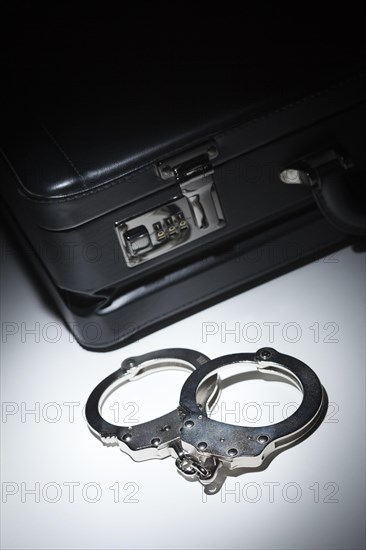 Pair of handcuffs and briefcase under spot light abstract