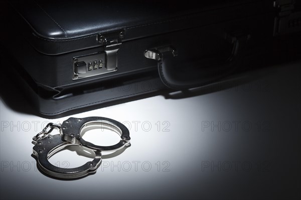 Pair of handcuffs and briefcase under spot light abstract