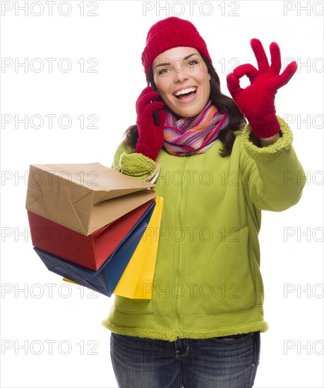 mixed-race woman holding shopping bags talking on her cell phone giving ok gesture isolated on white background