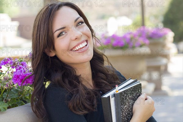 Portrait of pretty young female student carrying books on school campus