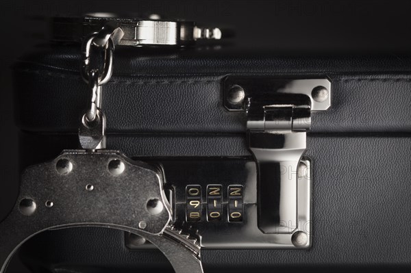 Pair of handcuffs on briefcase with the numbers 911 on lock