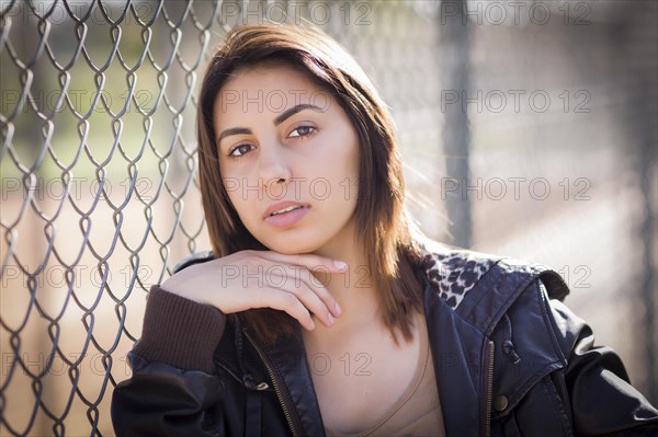 Beautiful mixed-race young woman portrait outside against chain link fence