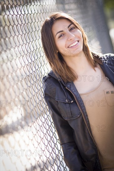 Beautiful mixed-race young woman portrait outside against chain link fence