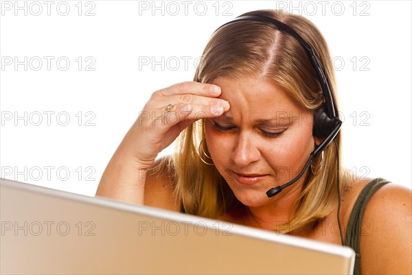 Businesswoman in front of a computer screen with phone headset showing signs of having a bad headache