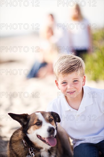 Handsome young boy playing with his dog at the beach