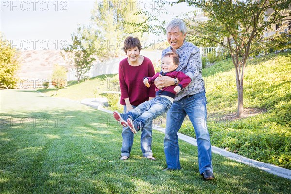 Happy chinese grandparents having fun with their mixed race grandson outside