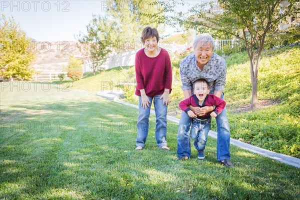 Happy chinese grandparents having fun with their mixed race grandson outside