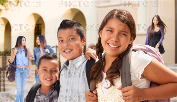 Young hispanic student children wearing backpacks on school campus