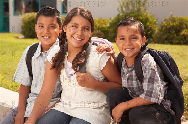 Young hispanic student children wearing backpacks on school campus