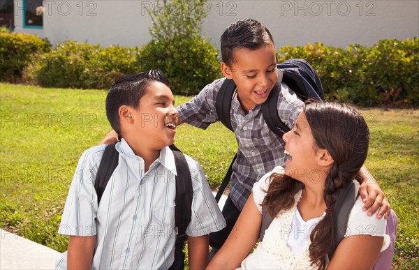 Young hispanic student children wearing backpacks on school campus