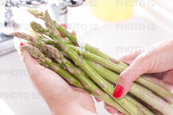 Woman washing asparagus in the kitchen sink