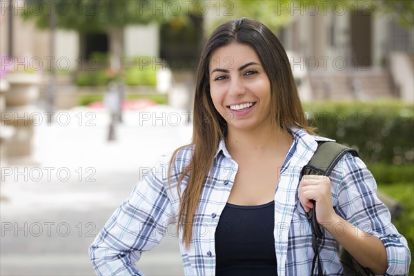 Attractive young mixed race female student portrait on school campus with backpack