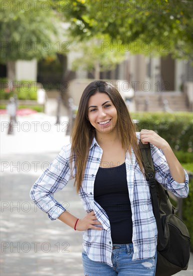 Attractive young mixed race female student portrait on school campus with backpack