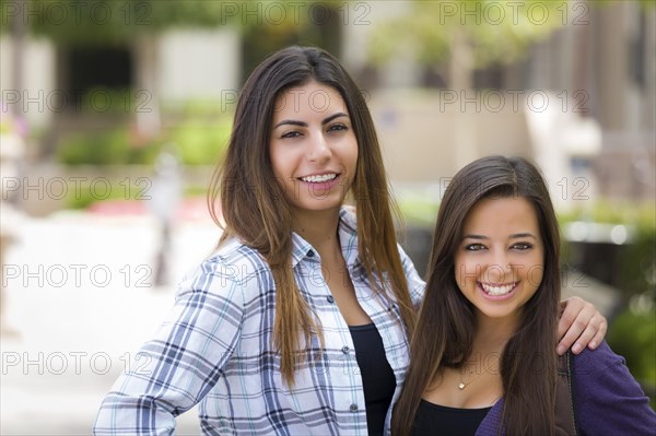 Portrait of two attractive mixed race female students carrying backpack on school campus