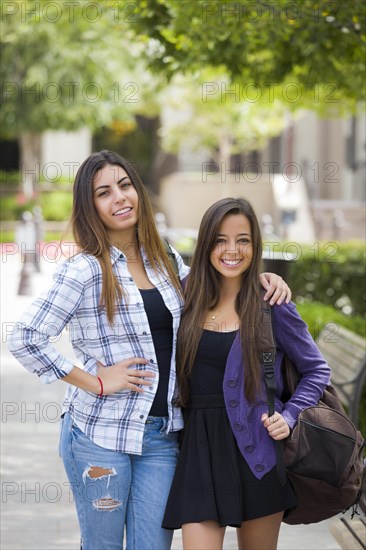 Portrait of two attractive mixed race female students carrying backpack on school campus