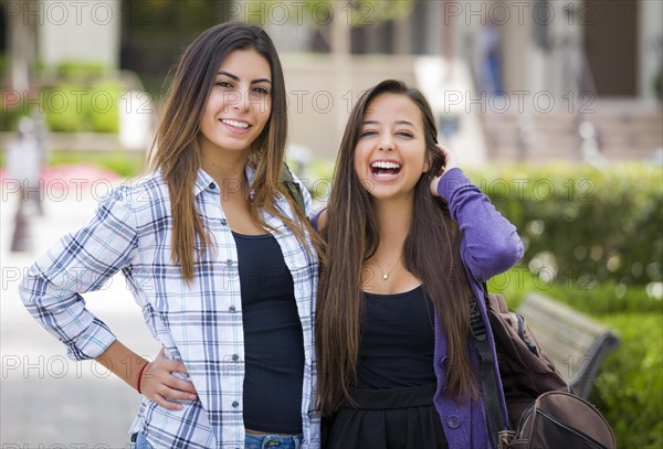 Portrait of two attractive mixed race female students carrying backpack on school campus