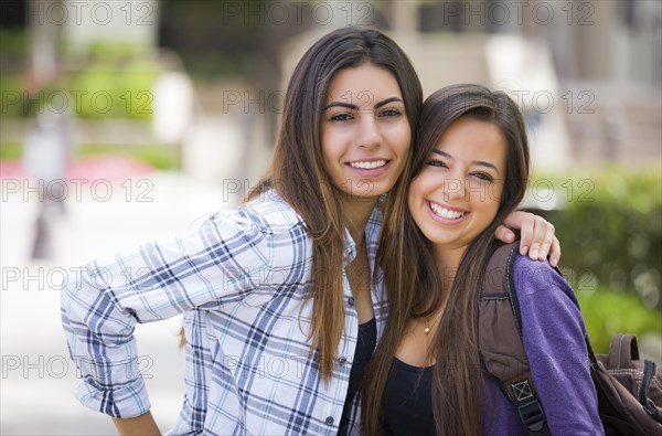 Portrait of two attractive mixed race female students carrying backpack on school campus