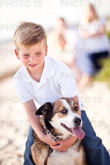 Handsome young boy playing with his dog at the beach