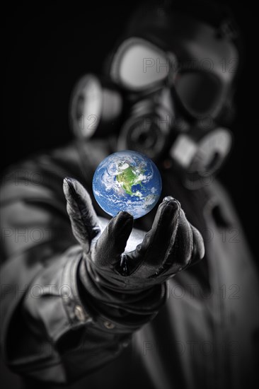 Menacing entity wearing fallout gas mask threatening planet earth with gloved hand