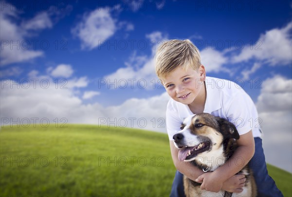 Handsome young boy playing with his dog on a lush green grass field