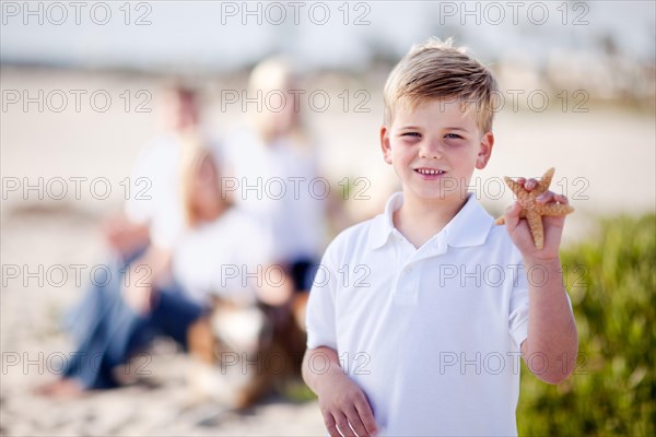 Cute little blonde boy showing off his starfish at the beach