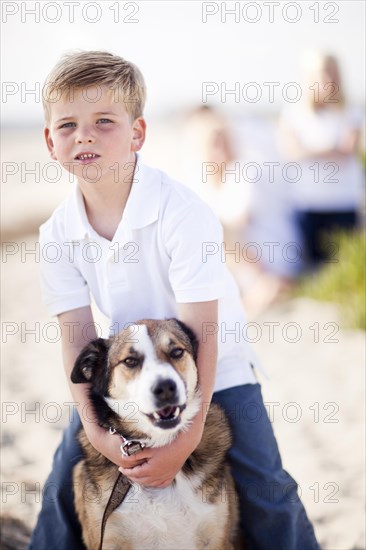 Handsome young boy playing with his dog at the beach