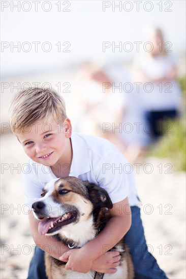 Handsome young boy playing with his dog at the beach